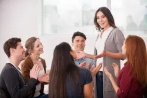 Frau, die etwas erzählt und für eine Gruppe von Menschen gestikuliert