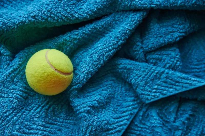 Gelber-Tennisball-auf-blauem-Handtuch