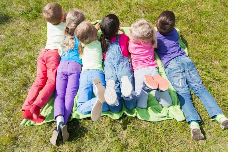Gruppe-von-Kindern-die-auf-Decke-oder-Abdeckung-im-Freien-liegen