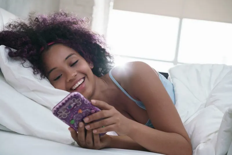 Teen-mit-Handy-fur-Chat-im-Bett-zu-Hause