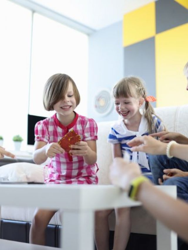Erwachsene-und-Kinder-sitzen-am-Tisch-halten-Spielkarten-und-lachen-frohlich