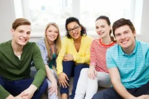 Fünf lächelnde Teenager, die Spaß zu Hause haben