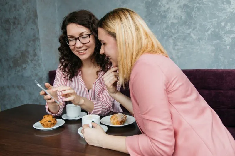 zwei-Frau-die-Kaffee-trinkt-und-ein-Smartphone-betrachtet