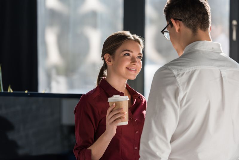 Attraktive junge Managerin mit Kaffee zum Flirten mit Kollegen