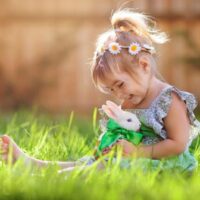 Nettes kleines Mädchen mit einem Häschen hat ein Ostern am grünen Gras