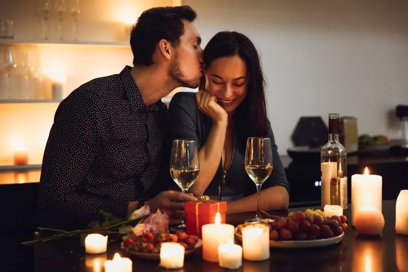 Schones-leidenschaftliches-Paar-das-ein-romantisches-Abendessen-bei-Kerzenlicht-zu-Hause-hat-und-kusst