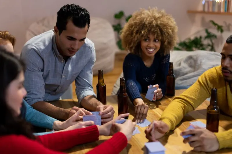 Tausendjahrige-erwachsene-Freunde-die-zu-Hause-zusammen-sind-Karten-spielen-Spiel-trinken