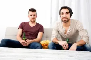 Zwei Freunde, die zu Hause fernsehen und trinken