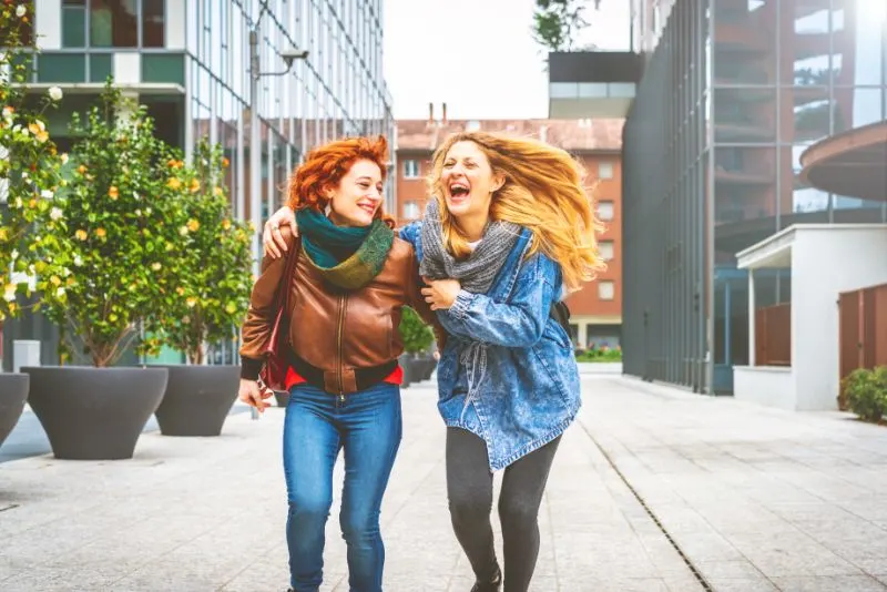 Zwei junge Frauen, die im Freien in der Stadt spazieren gehen, die Spaß haben