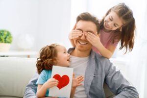 Glückliche Kinder mit Vatertagsgeschenken, die Spaß mit Vater halten Grußkarte mit ich liebe dich Papa Inschrift und Herz Symbol