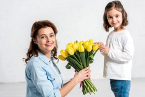 Glückliche Mutter, die Strauß der gelben Tulpen von der Tochter hält
