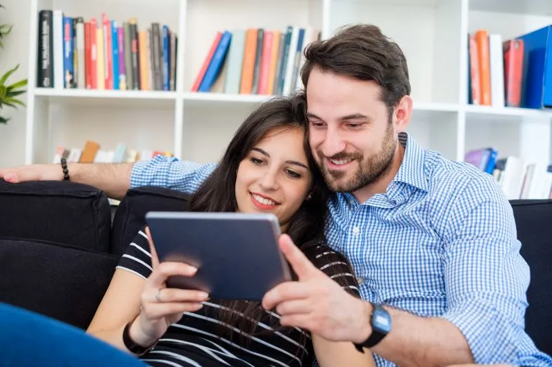 Junges Paar, das Internetmedieninhalt auf digitalem Tablett betrachtet