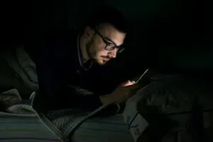 Mann, der sein Handy nachts ins Bett schaut