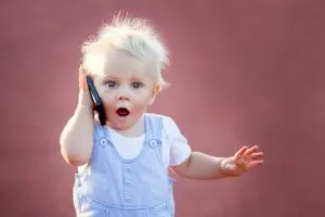 Netter kleiner Junge, der mit Handy im Park spielt, digitale Technologien in den Händen eines Kindes. Porträt des Kleinkindes mit Smartphone