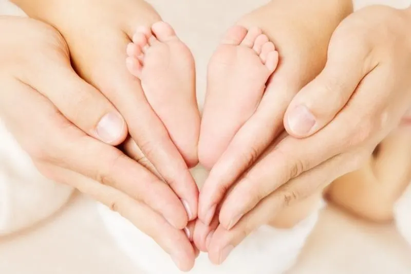 Neugeborene-Babyfuse-in-den-Handen-der-Eltern.-Liebe-simbol-als-Herzzeichen-1