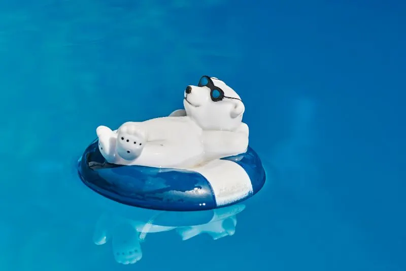 Pooldekoration-in-Form-eines-entspannten-Badeeisbaren-mit-Sonnenbrille-und-Schwimmring-auf-blauem-Wasser.