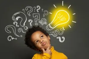 Denkender Kinderjunge auf schwarzem Hintergrund mit Glühbirne und Fragezeichen. Brainstorming und Ideenkonzept