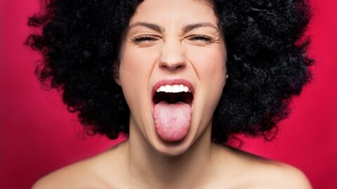 Frau mit Afro, die ihre Zunge herausstreckt