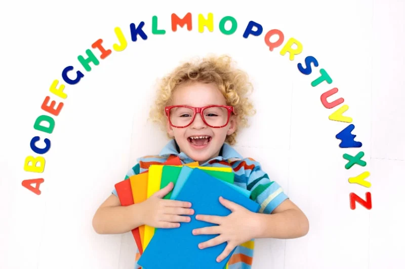 Gluckliches-Vorschulkind-das-das-Lesen-und-Schreiben-lernt-und-mit-bunten-Buchstaben-spielt