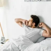 Hübscher Mann, der morgens gähnt und im Bett aufwacht