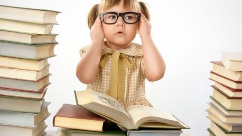 Kleines Mädchen mit Büchern, die Brille tragen