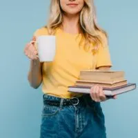 Mädchen hält Bücher und Tasse Kaffee