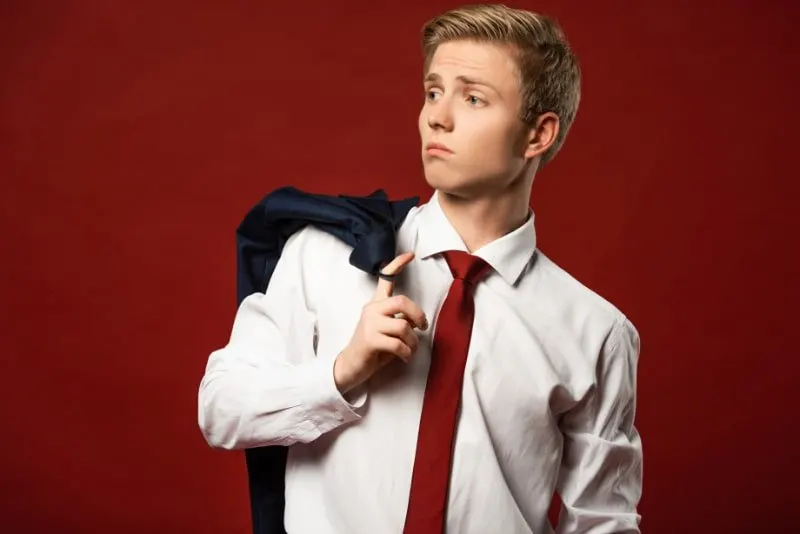 Selbstbewusster-Mann-mit-Jacke-am-Finger-auf-rotem-Hintergrund
