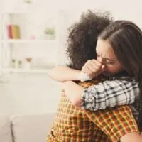 Frau umarmt ihren depressiven Freund zu Hause