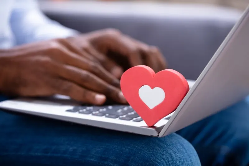 Nahaufnahme-der-roten-Herzform-auf-der-Tastatur-wahrend-die-Hand-des-Mannes-mit-Laptop