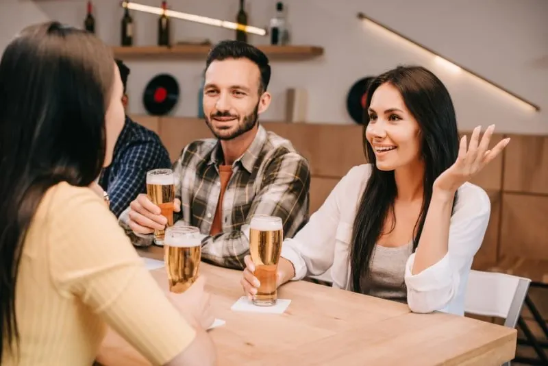 Frohliche-multikulturelle-Freunde-die-sich-unterhalten-wahrend-sie-in-der-Kneipe-Bier-trinken
