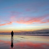 Mann, der schönen Sonnenuntergang am Strand betrachtet