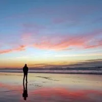 Mann, der schönen Sonnenuntergang am Strand betrachtet