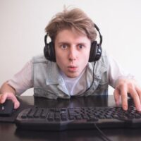 Porträt eines lustigen Spielers mit erstauntem Gesicht beim Spielen auf einem Computer.