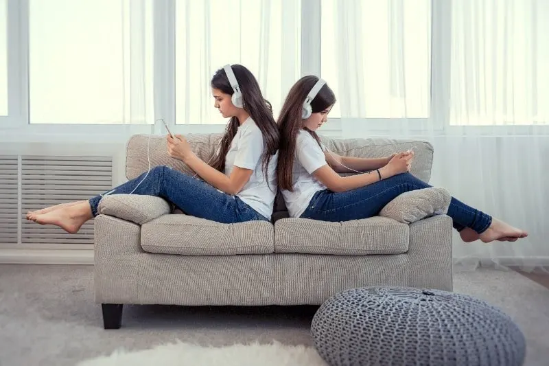 Schwestern-im-Teenageralter-mit-Smartphone-und-Kopfhorern-die-Musik-horen-und-in-sozialen-Netzwerken-kommunizieren