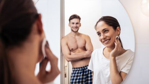 Sexy Ehemann mit schönen Bauchmuskeln beobachtet seine Frau beim Abschminken