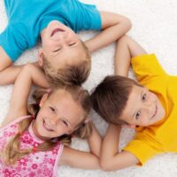 Drei Kinder, die im Kreis auf dem Boden liegen