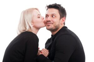 Hübsche Frau, die einen Kuss auf die Wange des Freundes gibt