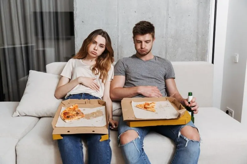 Ungluckliches-Paar-hat-beim-Zusammensitzen-zu-viel-Pizza-gegessen
