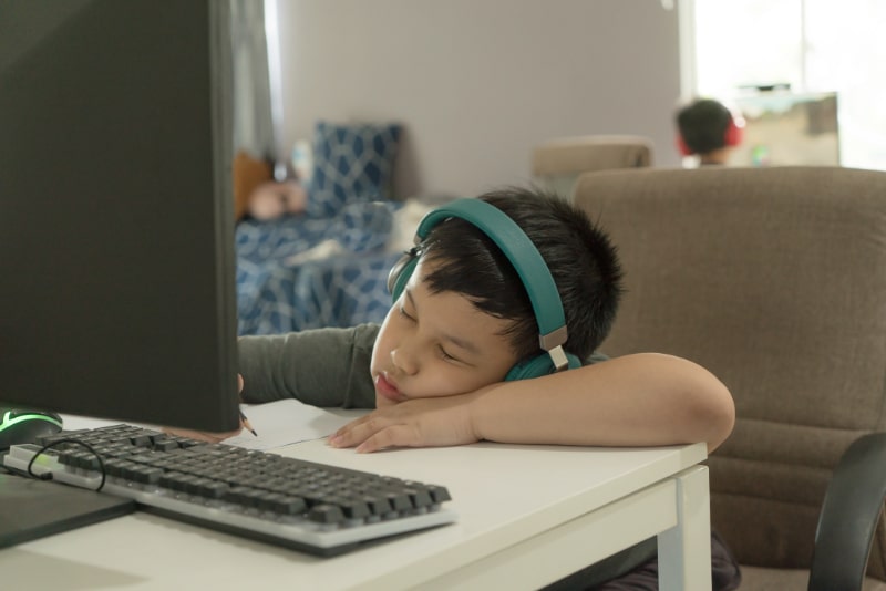 Muder-asiatischer-Schuljunge-schlaft-wahrend-des-Online-Unterrichts-ein