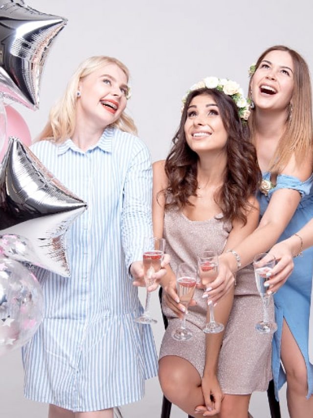 Glückliche Freundinnen, die eine Brille mit Alkohol und Luftballons halten, während sie Junggesellenabschied feiern.