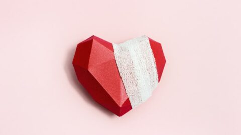 Ansicht von oben mit verwundeten Herzen rot. Verbundenes polygonales Papierherz auf rosa Hintergrund. Gesundheitswesen und medizinisches Konzept