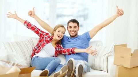 Lächelndes Paar, das sich auf dem Sofa im neuen Zuhause entspannt