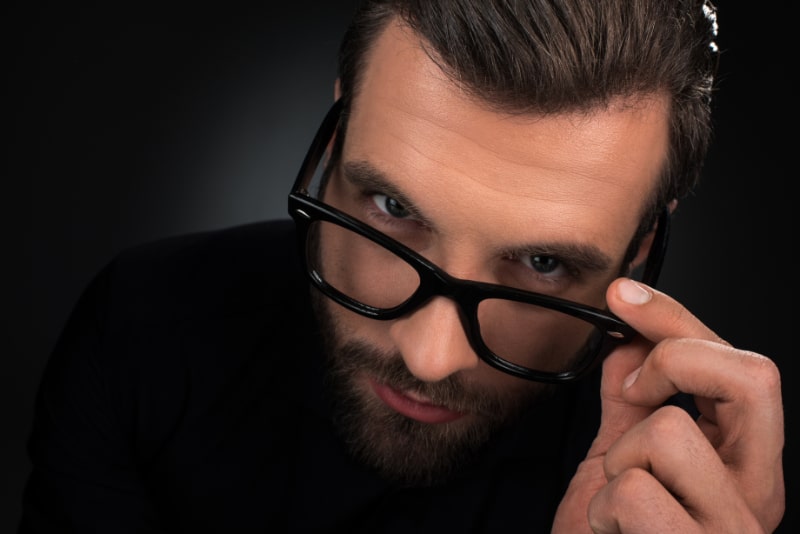 Portrat-eines-Mannes-mit-Brille-der-isoliert-auf-Schwarz-in-die-Kamera-schaut