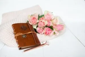 Rosa Rosen und ein Ledernotizbuch auf einer rosa Decke