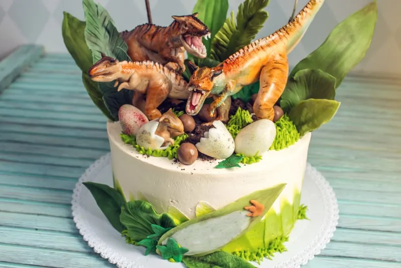 Weiser-Kuchen-fur-Kinder-dekoriert-mit-Dinosauriern-im-Dschungel-der-Jurazeit.-Konzeptideen-Desserts-fur-Kinder