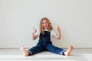mädchen sitzt auf dem boden und hält daumen hoch