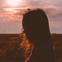 Silhouette-einer-Frau-im-Feld-bei-Sonnenuntergang